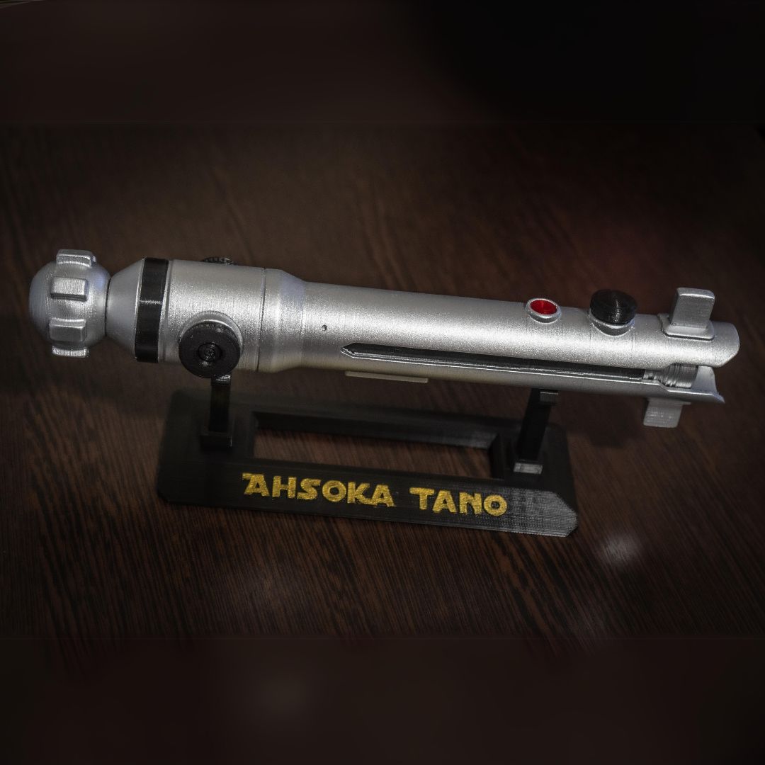 Ahsoka Tano lightsaber replica on black stand with yellow lettering, silver Star Wars cosplay prop detailed and durable