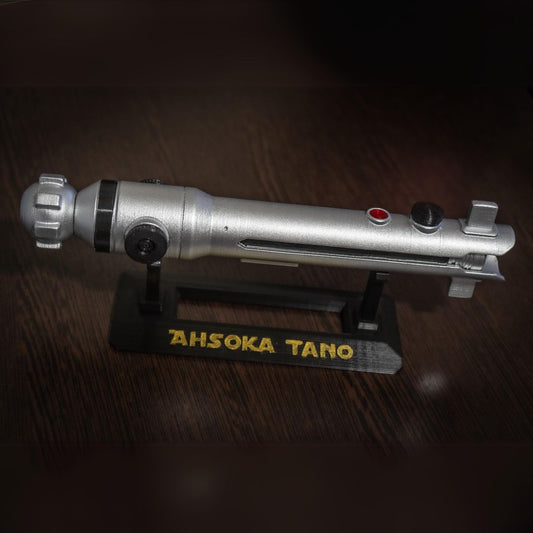 Ahsoka Tano lightsaber replica on black stand with yellow lettering, silver Star Wars cosplay prop detailed and durable