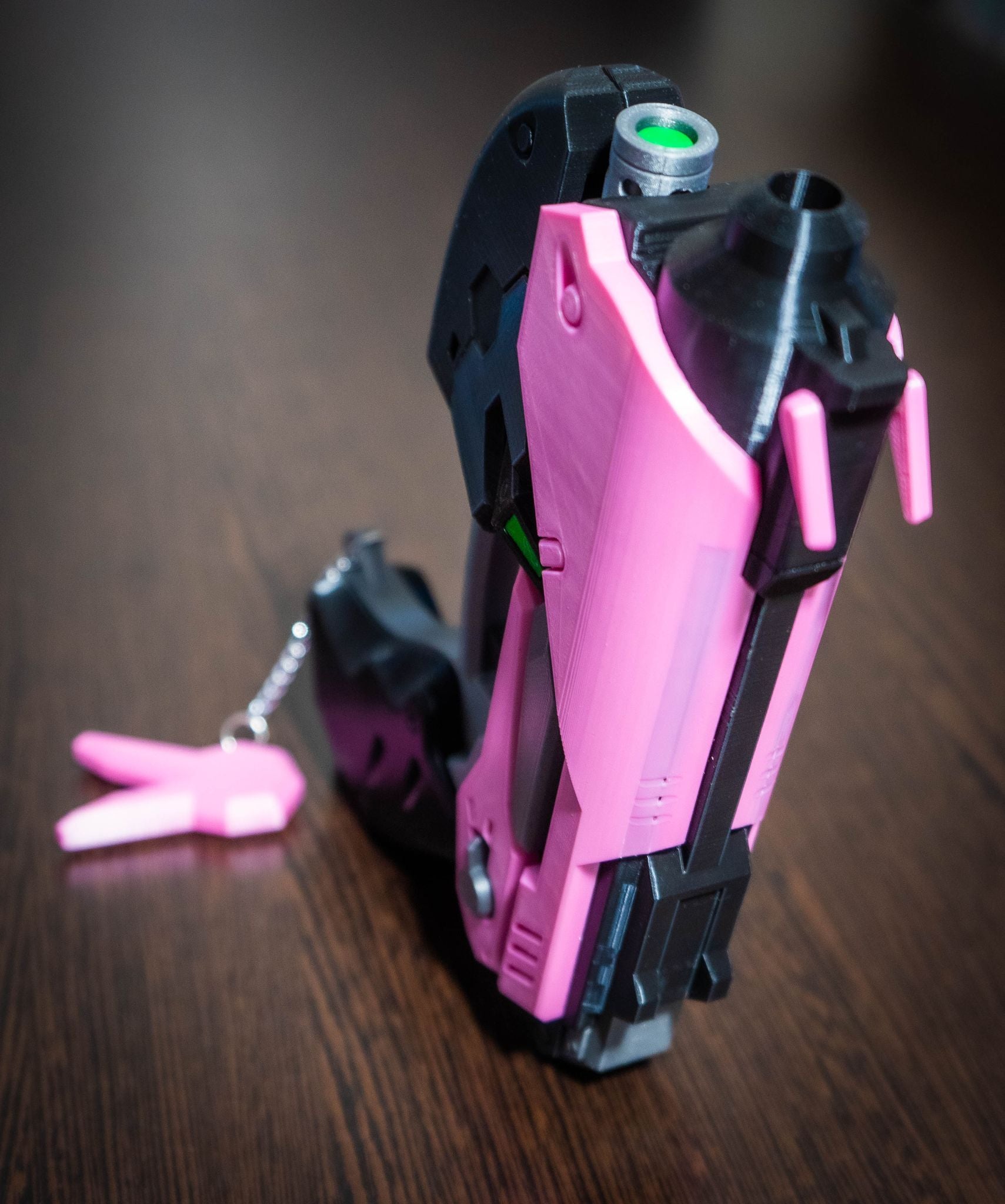D.Va cosplay gun prop replica in pink and black colors with detailed design on wooden surface