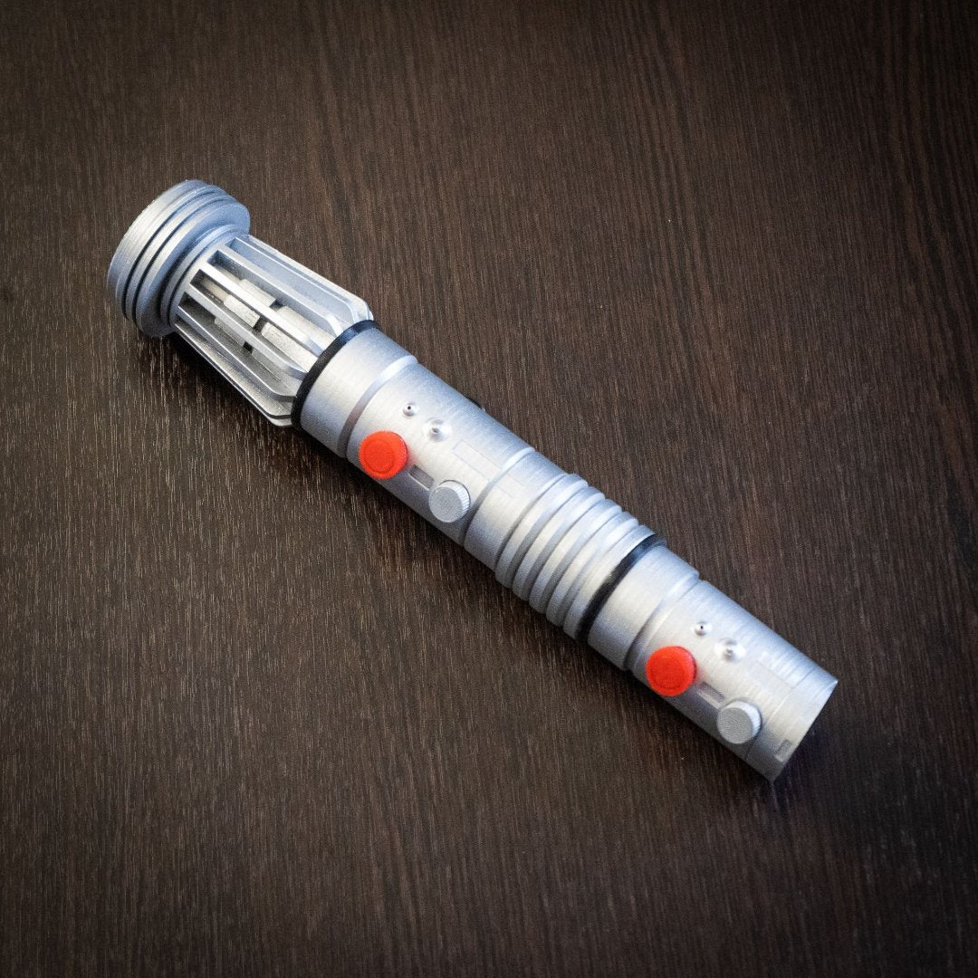 Darth Maul single-bladed lightsaber replica prop in silver with red buttons on dark wooden surface