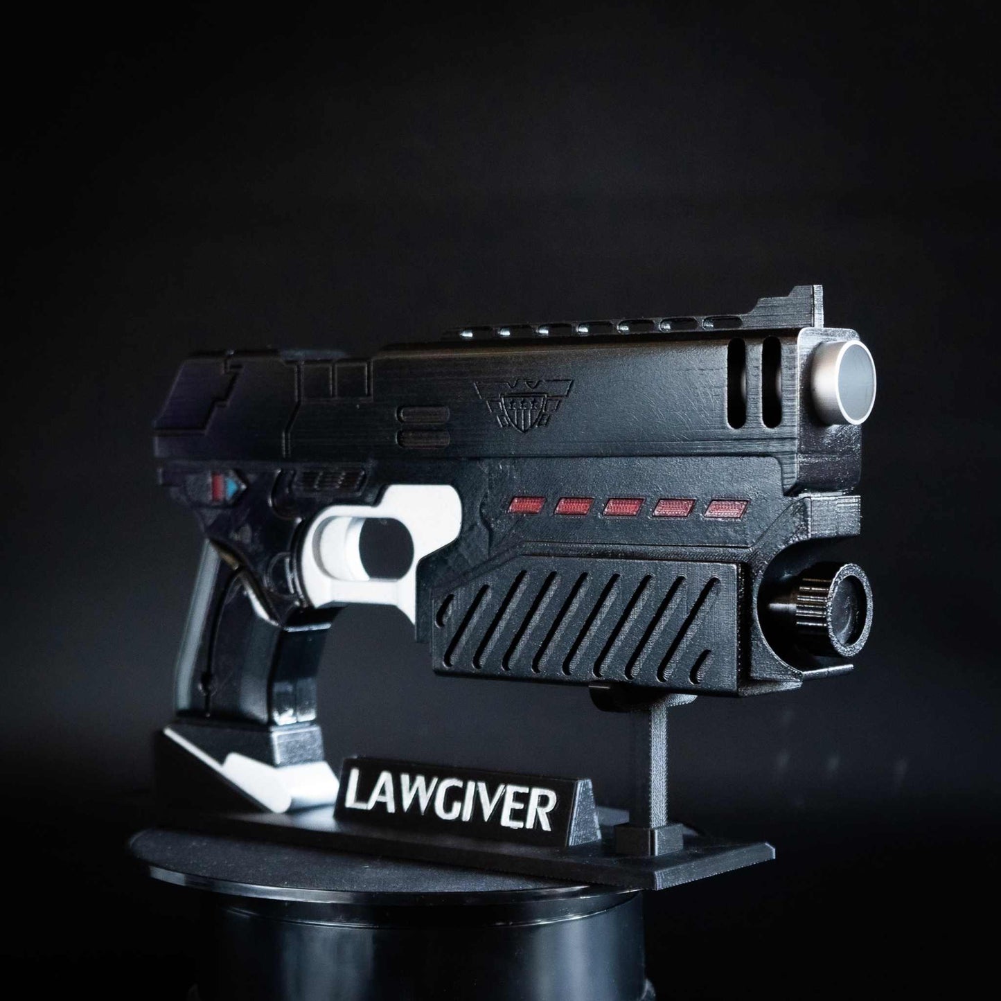 Judge Dredd Lawgiver cosplay prop gun replica in black with red accents on display stand