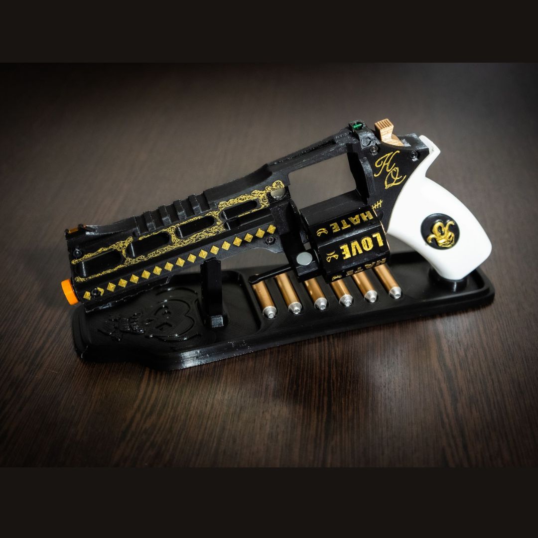 Movie-accurate Harley Quinn's Revolver cosplay prop with black and white design, gold detailing, and six bullets on a black stand.