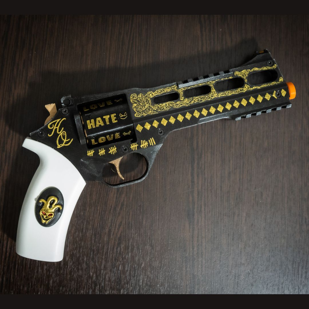 3D printed Harley Quinn's Revolver replica with black and gold details, white handle, orange safety tip, functional prop for cosplay and display