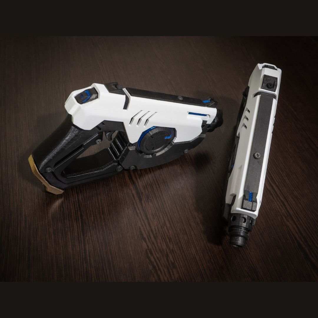 White and black Tracer's Pulse Pistols cosplay replica gun set on dark wooden surface, 3D printed costume prop without LEDs.