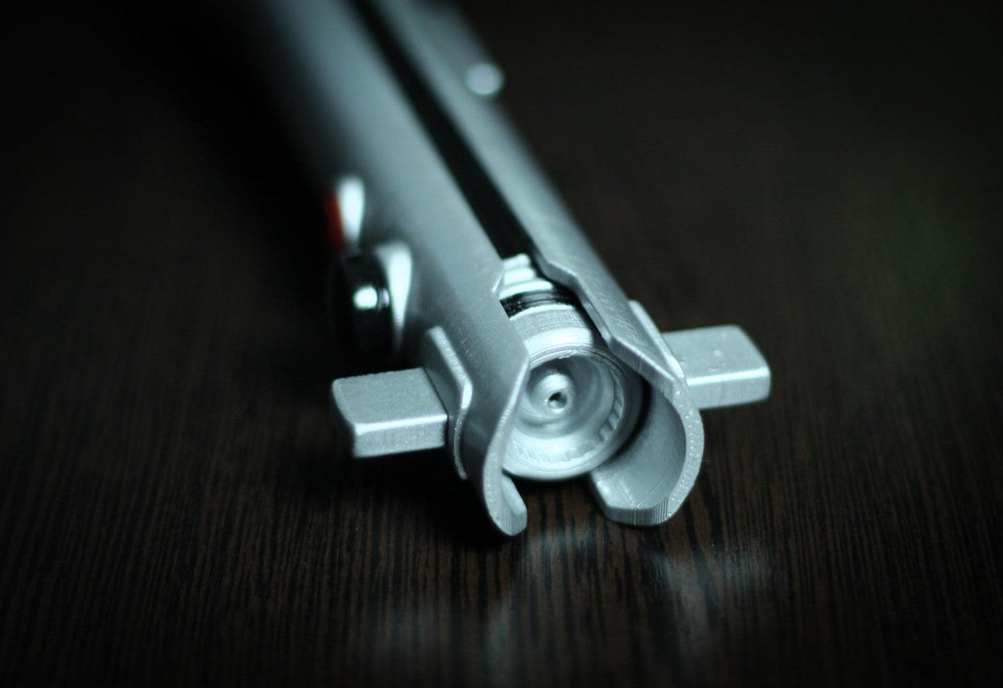 Close-up of the silver Ahsoka Tano lightsaber replica hilt on dark wood surface for Star Wars cosplay replica props