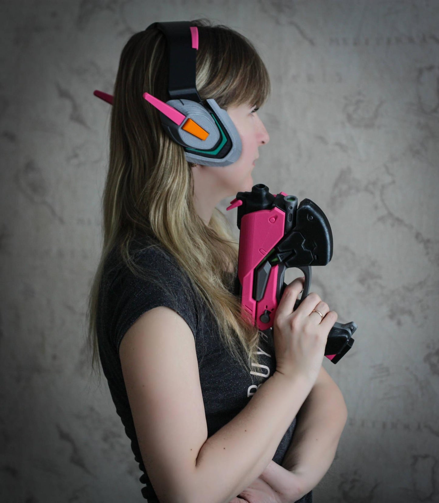 Officer Dva headset props worn by cosplayer holding pink and black gaming gun replica