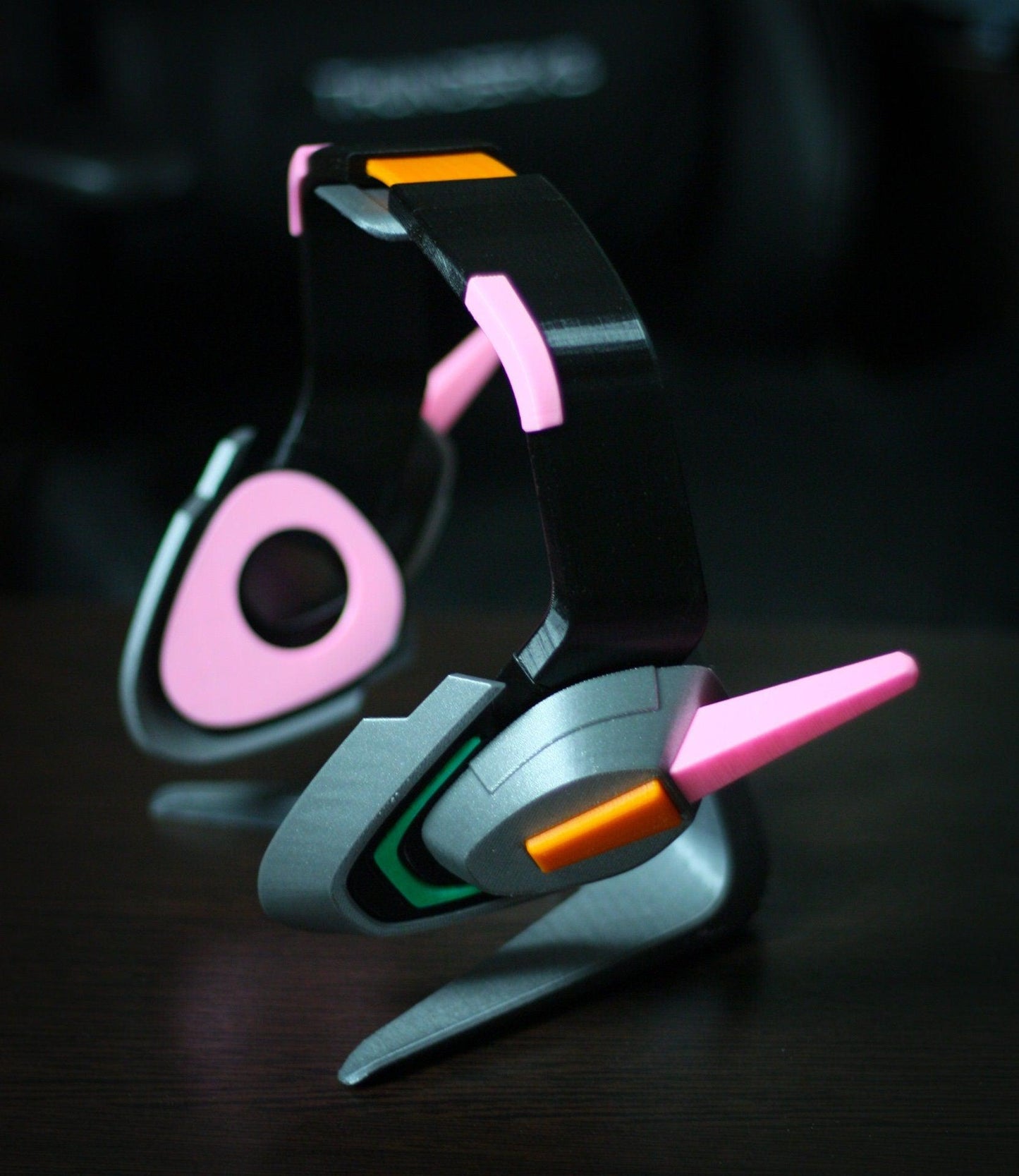 Officer Dva headset prop with black, pink, and orange cosplay headphones on dark surface