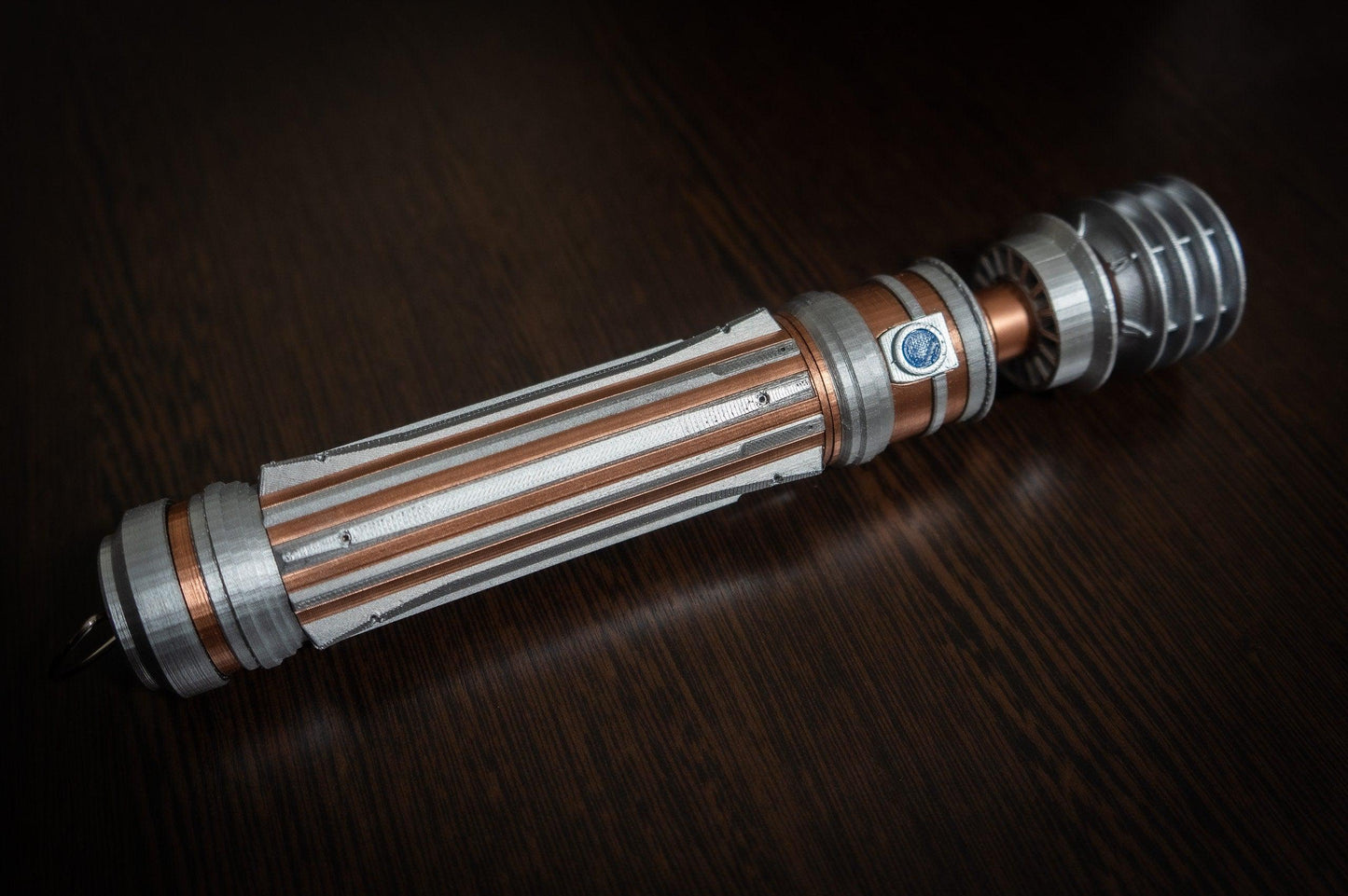 Leia Organa Lightsaber replica prop from Star Wars IX Rise of Skywalker with detailed silver and copper design on dark wooden background