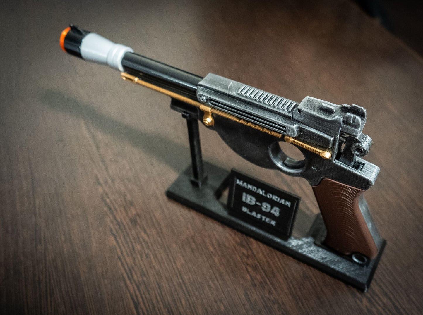Mandalorian Blaster IB-94 Star Wars replica prop on display stand with orange safety tip for cosplay
