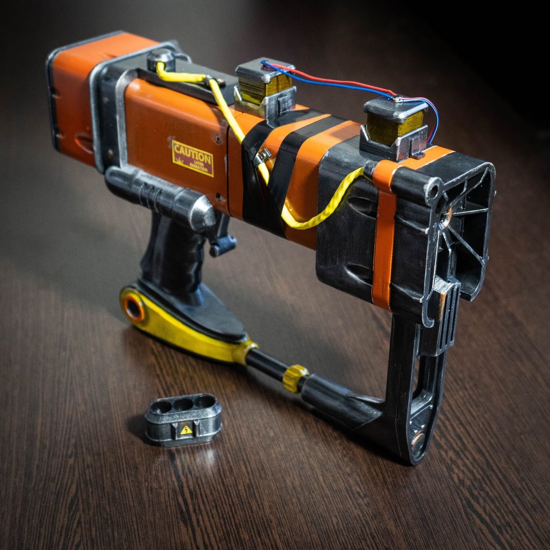 3D printed Fallout New Vegas AEP7 laser pistol cosplay prop with weathered orange and black design on wooden surface