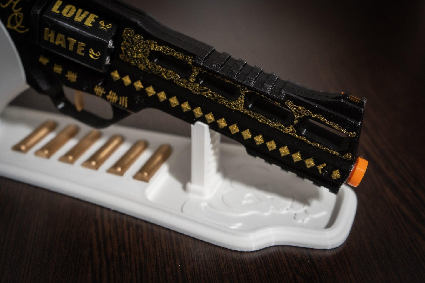 Close-up of Harley Quinn's Revolver movie-accurate cosplay prop with black and gold details on a white stand and six bullets displayed.