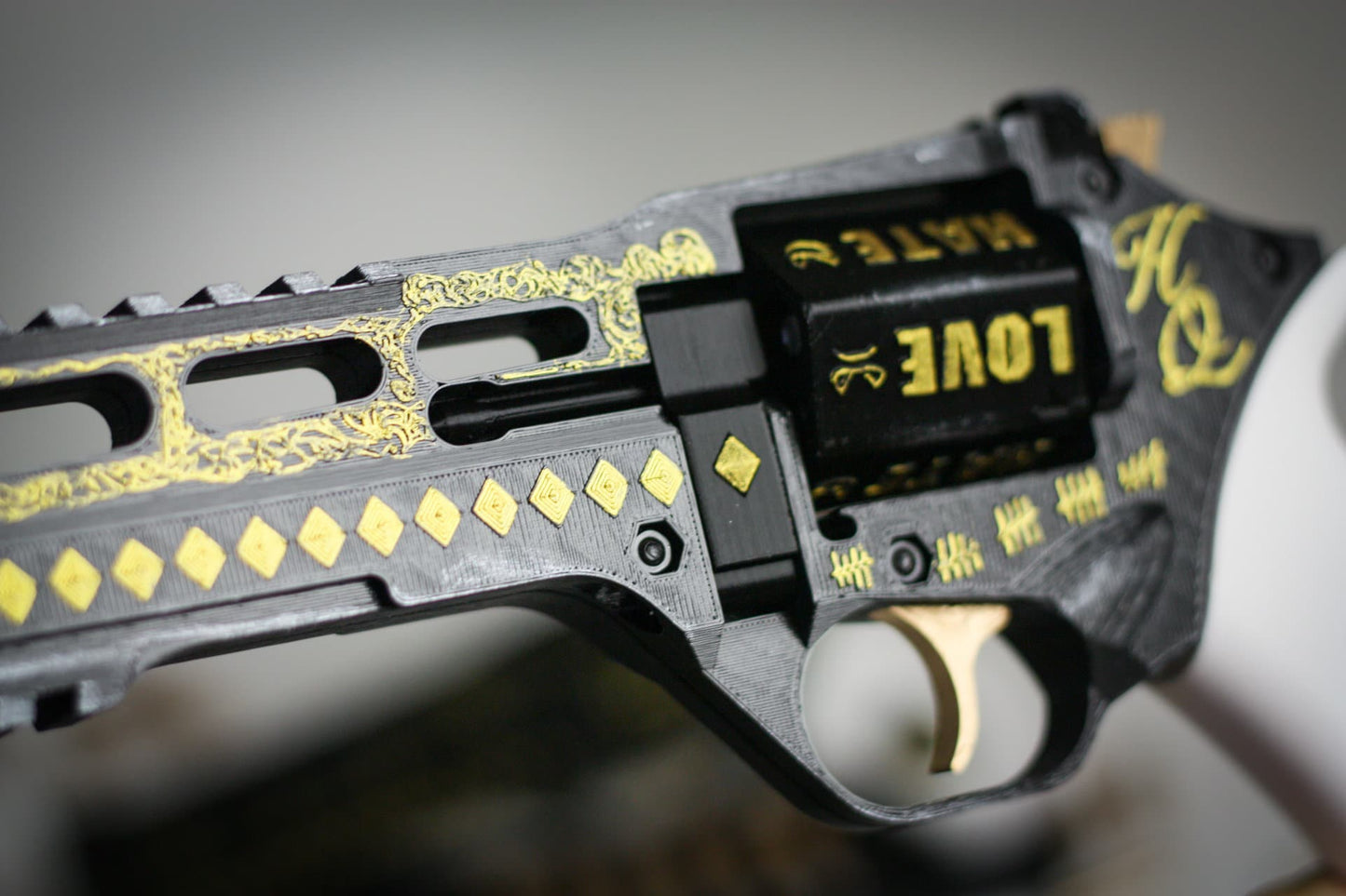 Close-up of Harley Quinn's movie-accurate black and gold painted revolver prop with detailed engravings and functional trigger.
