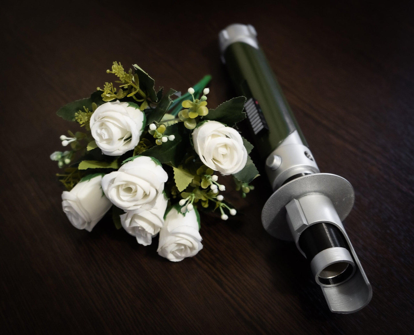 Star Wars inspired bridal bouquet holder shaped like Kanan Jarrus lightsaber with white roses on dark wood background