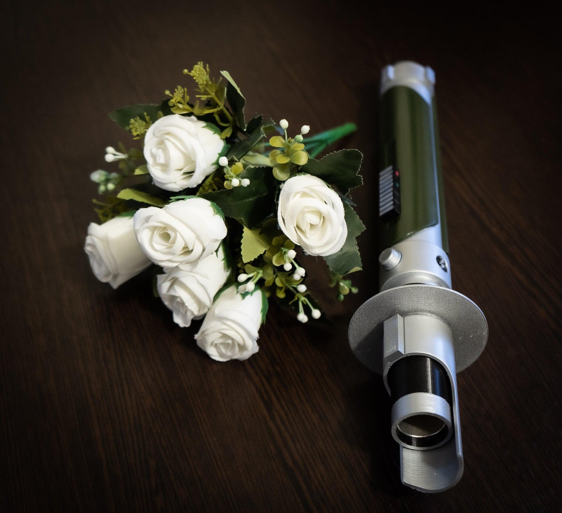 Star Wars inspired bridal bouquet holder resembling Kanan Jarrus lightsaber with white roses on wooden surface