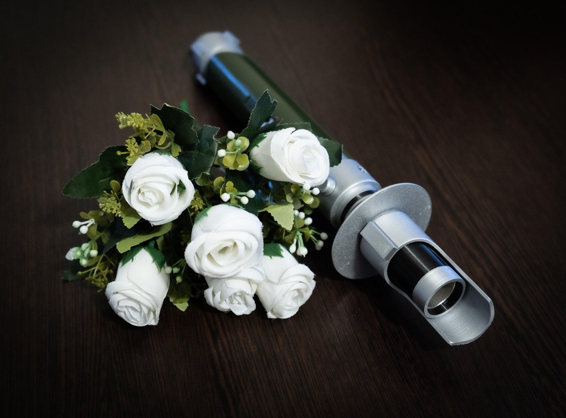 Star Wars inspired Kanan Jarrus lightsaber bridal bouquet holder with white roses on dark wood surface