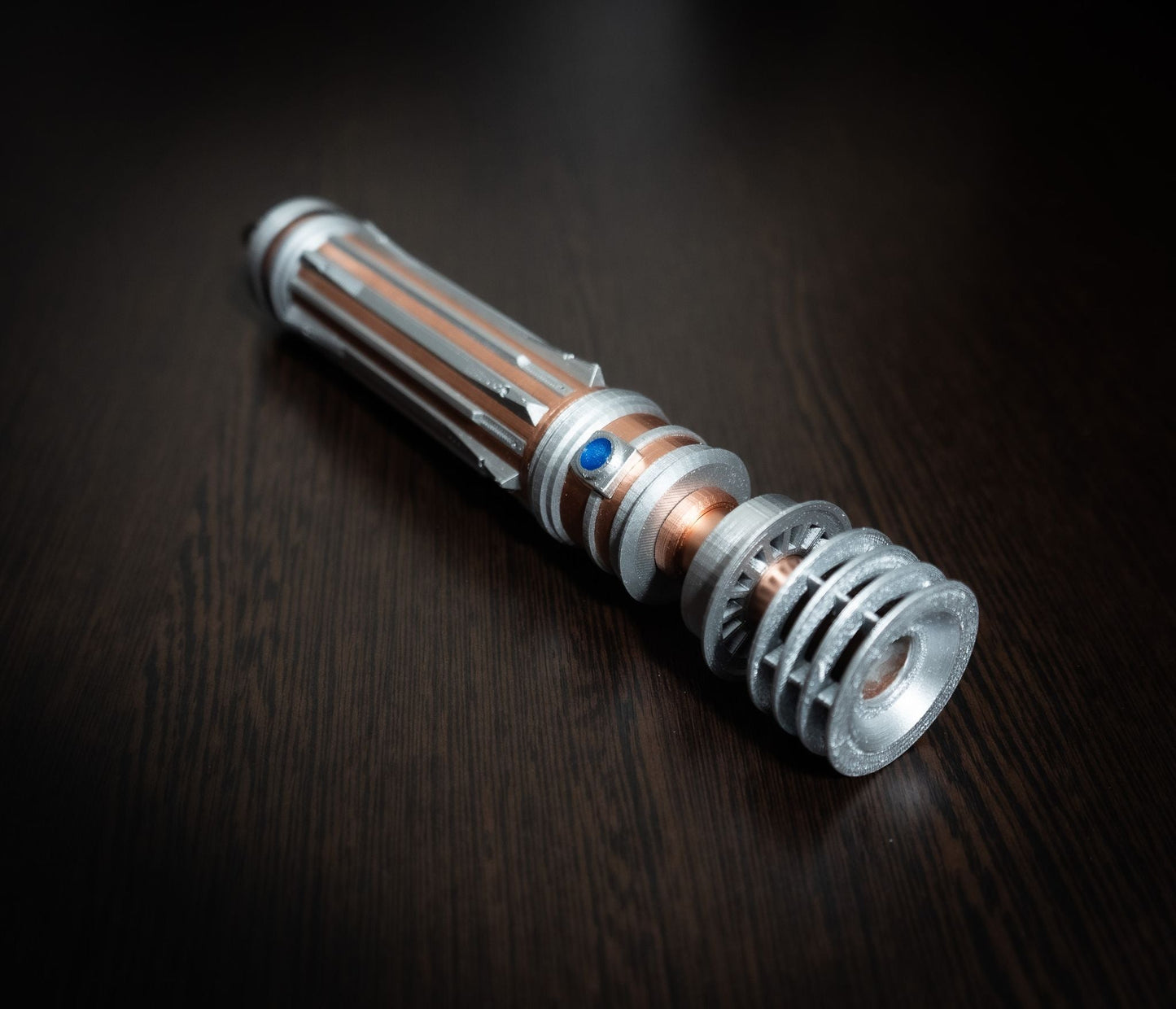 Star Wars inspired bridal bouquet holder modeled after Leia Organa’s lightsaber with copper and chrome finish on dark wood surface