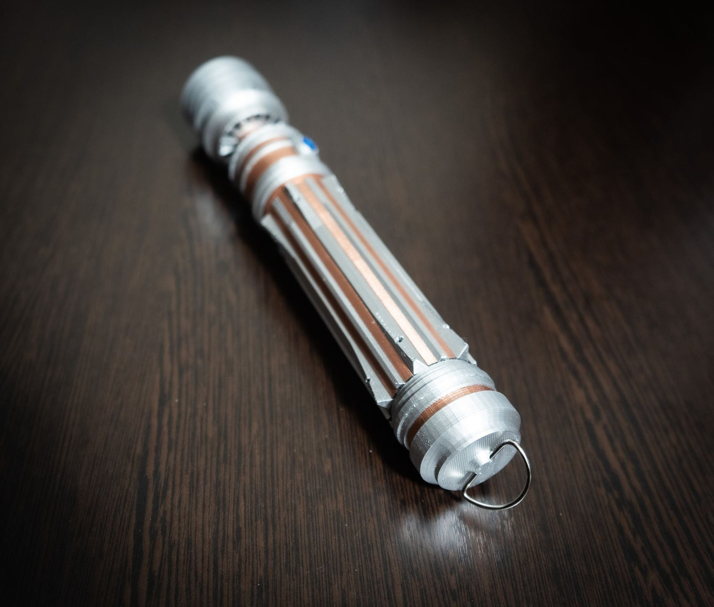 Star Wars inspired bridal bouquet holder modeled after Leia Organa's lightsaber in silver and copper tones on dark wooden surface
