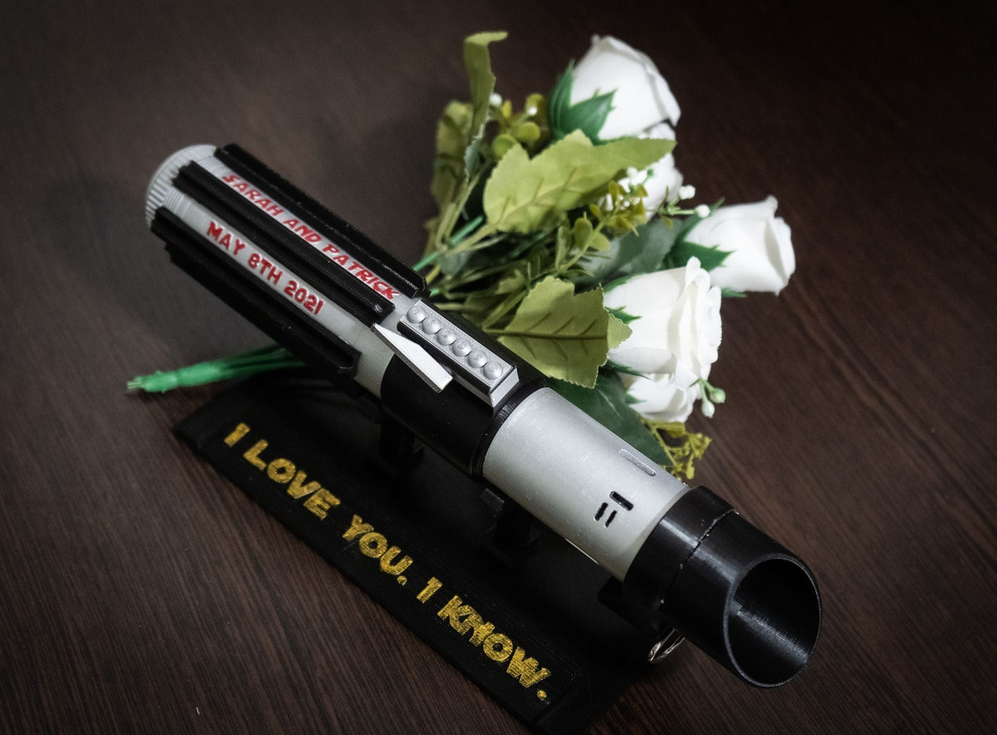 Star Wars inspired Darth Vader lightsaber bridal bouquet holder with personalized text and white roses on wooden surface