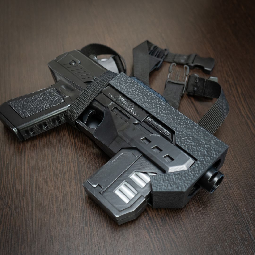 Black tactical gun with straps on a wooden surface