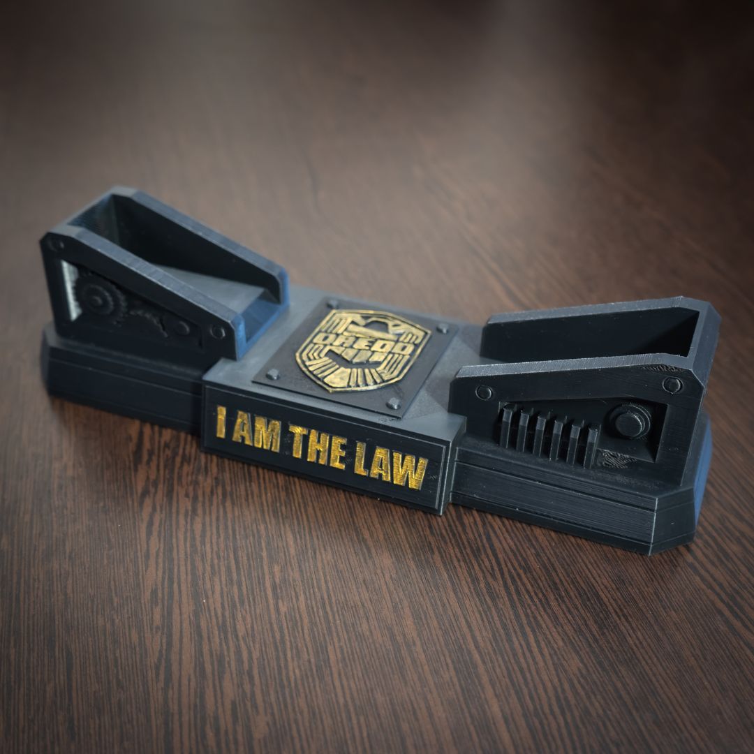 Black metal device with 'I AM THE LAW' text on a wooden surface