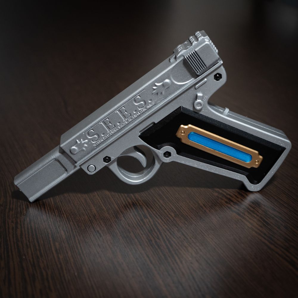 Silver gun-shaped object with blue slide on a dark wooden surface