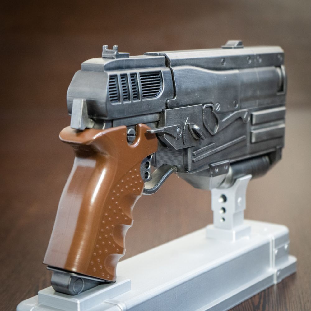 Toy gun with a brown handle on a white stand against a brown background