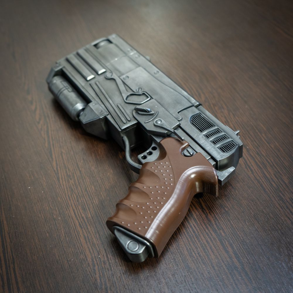 Toy gun with brown handle and gray body on a wooden surface