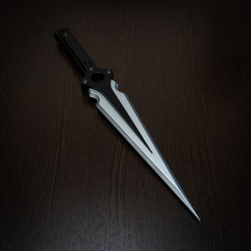 Futuristic knife with a metallic blade and black handle on a dark wooden surface