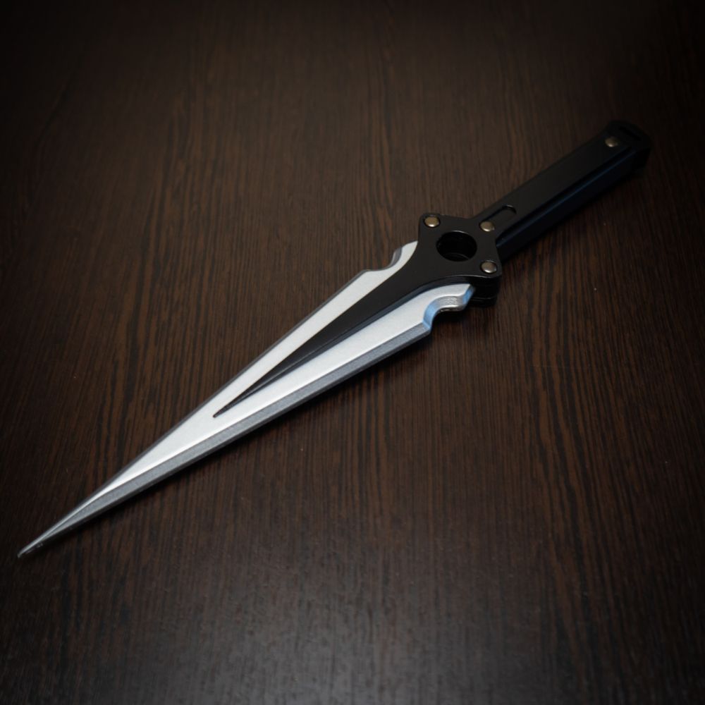 Futuristic knife with a metallic blade and black handle on a dark wooden surface