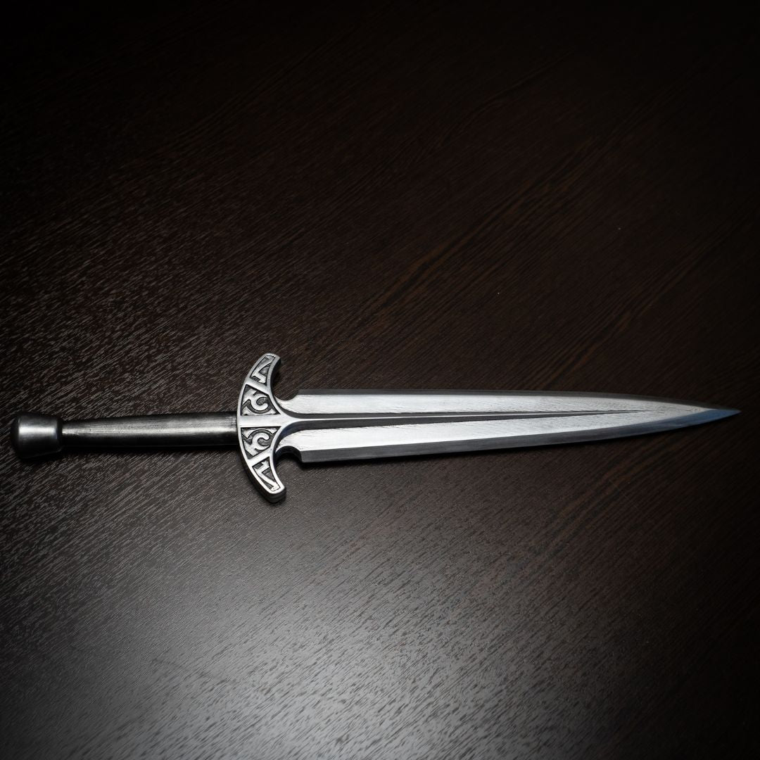 Decorative sword with a detailed hilt on a dark wooden surface