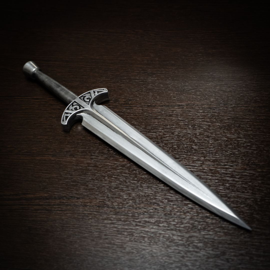 Decorative sword with a silver blade and handle on a dark wooden surface