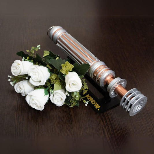 Star Wars inspired bridal bouquet holder designed as Leia Organa's lightsaber in copper and chrome colors holding white roses on dark wooden surface